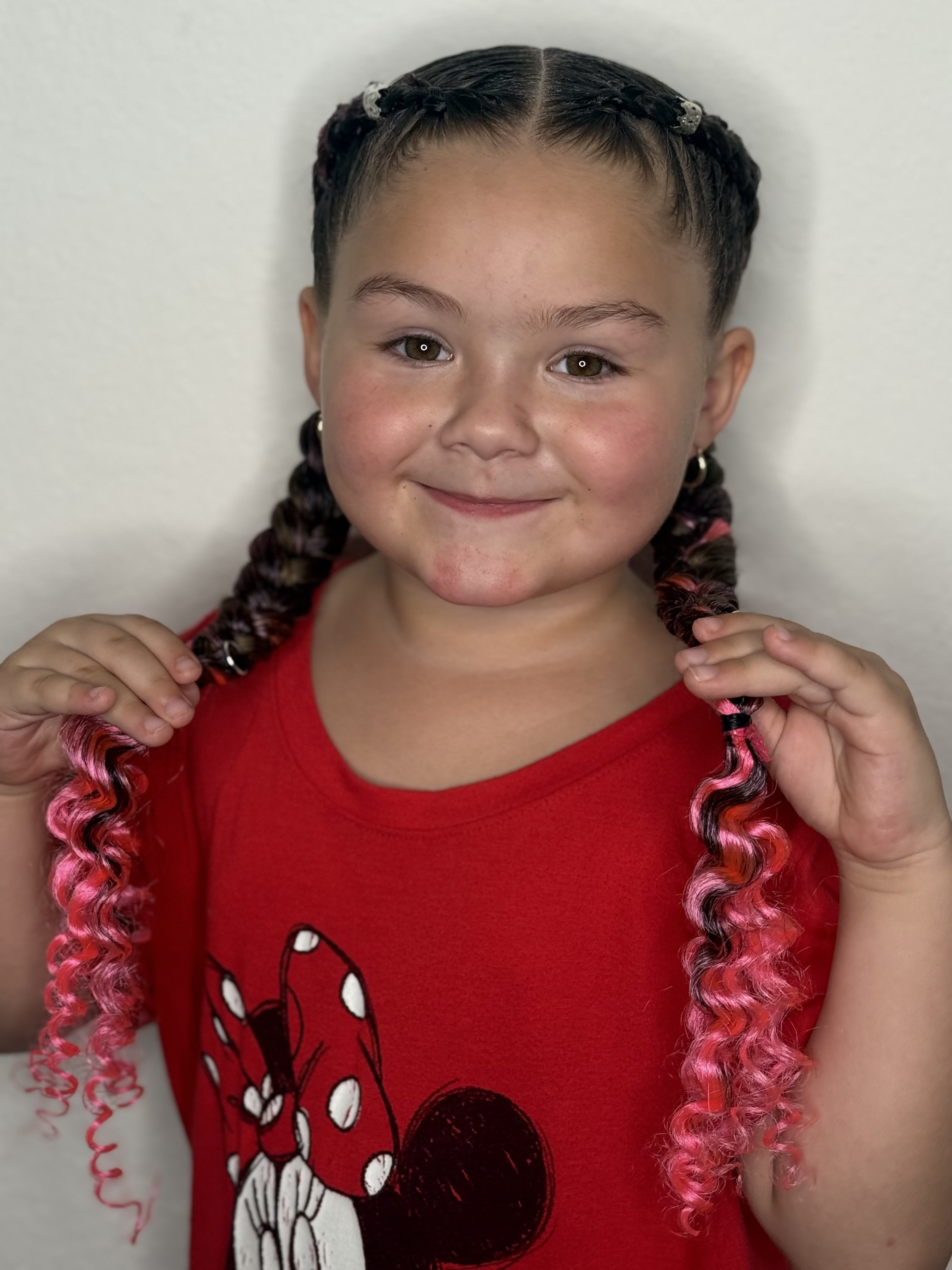 Child smiling with pink braids by Yulis in South Miami