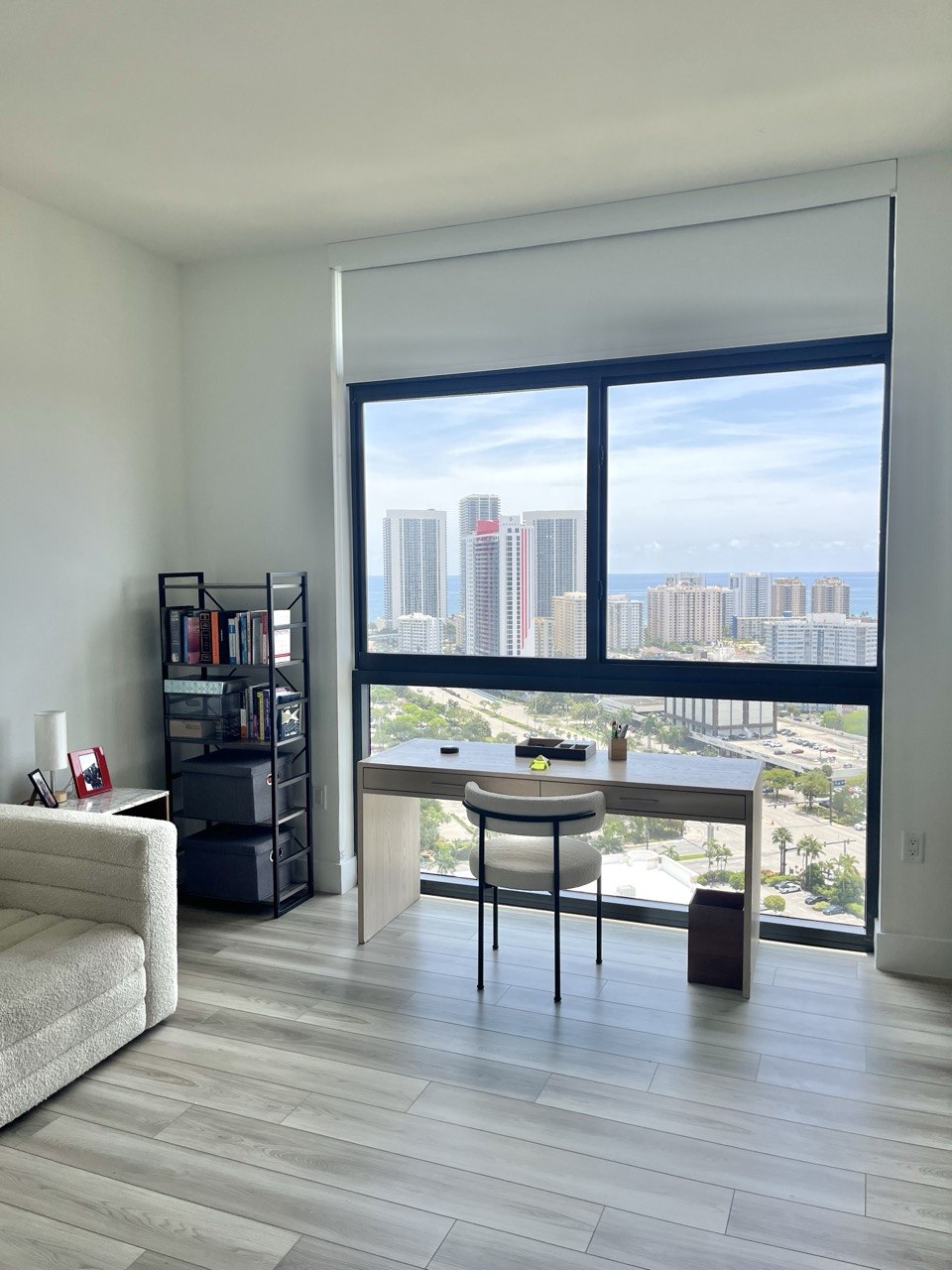 Home office with desk, organized bookshelf, and a floor-to-ceiling view of the Fort Lauderdale skyline